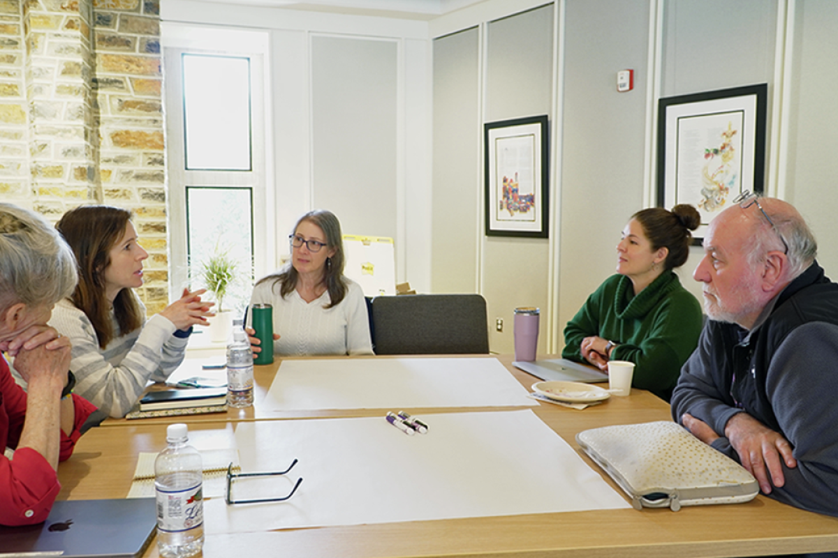 People engage in discussion around a table.