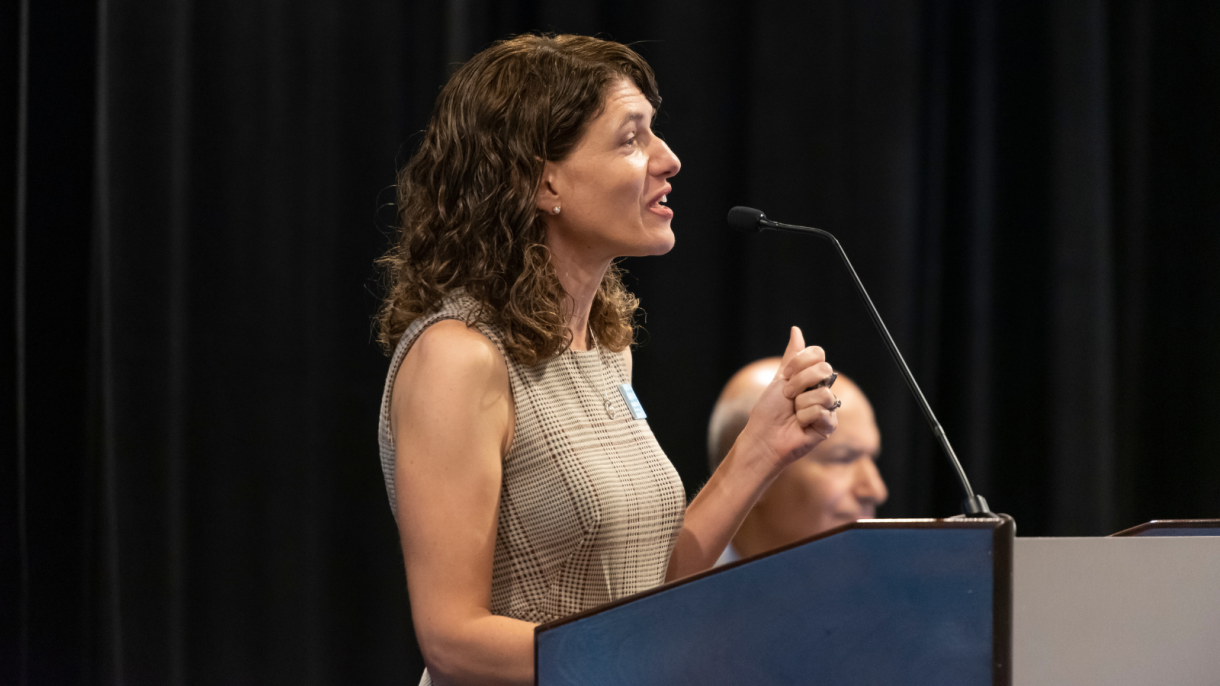 Maria Wisdom speaks at the podium.