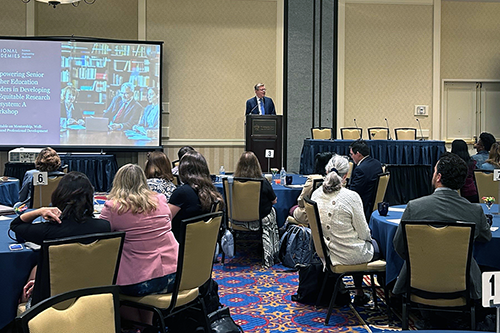 President Price speaks at the podium as participants listen.